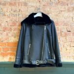 Front of black hooded women’s sheepskin biker jacket with belt and zip pockets