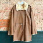 Front view of tan women’s sheepskin coat with cream collar and zip pockets