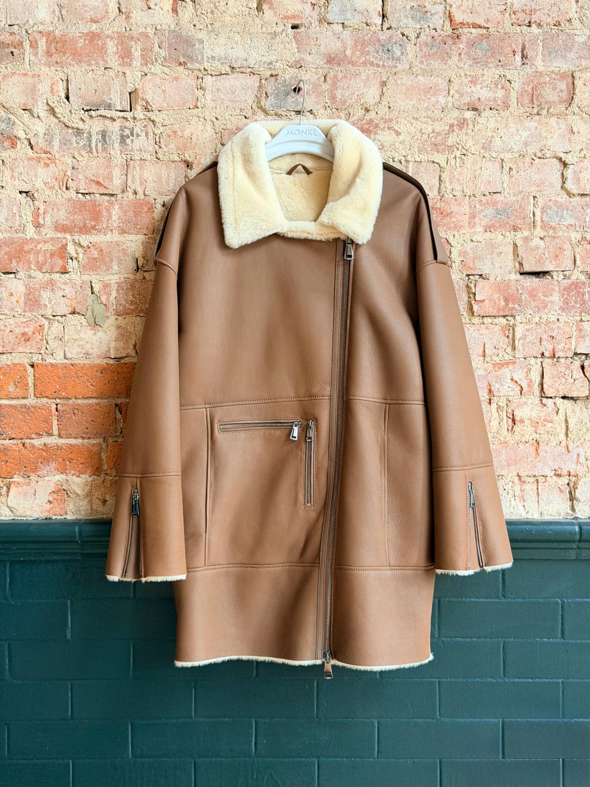Front view of tan women’s sheepskin coat with cream collar and zip pockets
